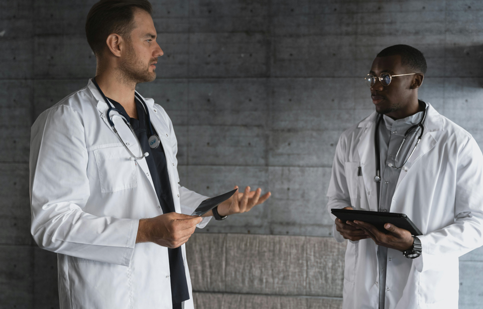 Two doctors engaged in conversation in a well-lit office, discussing patient care and treatment options.